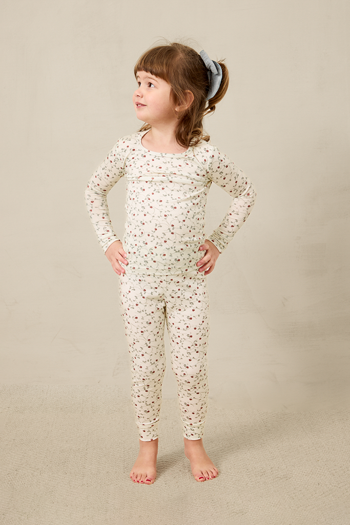 Young girl wearing a strawberry pajama set on a beige background