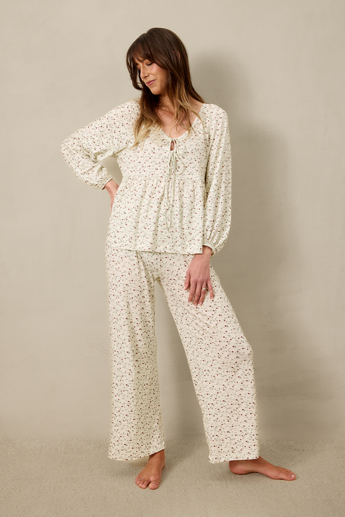 Woman wearing strawberry print pajama set against a beige background