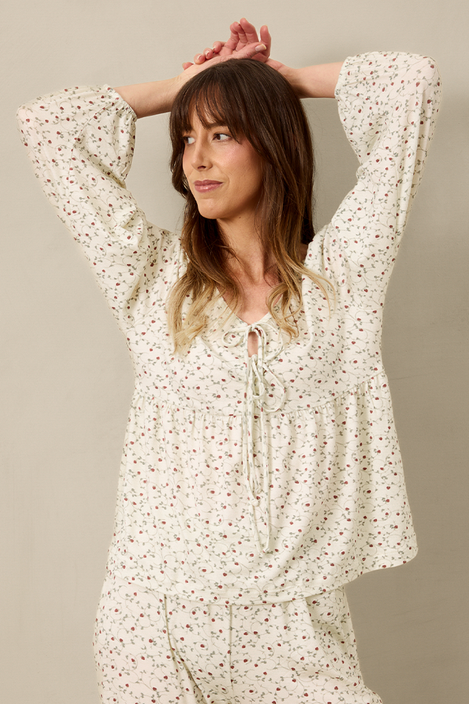 Woman wearing a white strawberry pajama set against a beige background
