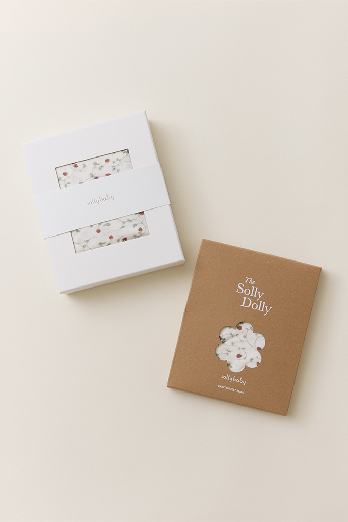 The Strawberry Wrap in white packaging alongside The Strawberry Solly Dolly in a kraft box, both featuring a dainty hand-painted strawberry vine print.