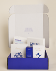 Collection of baby products in a box with visible branding on a beige background
