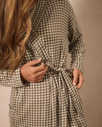 Woman wearing a green and white gingham robe against a beige background